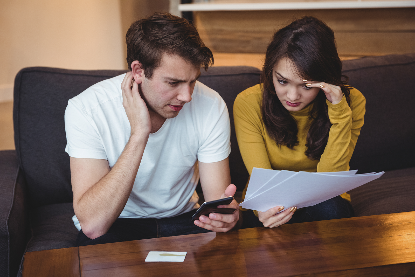 casal-sentado-no-sofa-discutindo-documentos-financeiros-na-sala-de-estar1